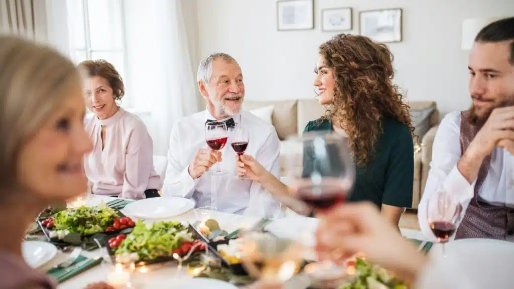 Young man with a beard and dark hair smiles slightly while looking to the left at a dinner table.