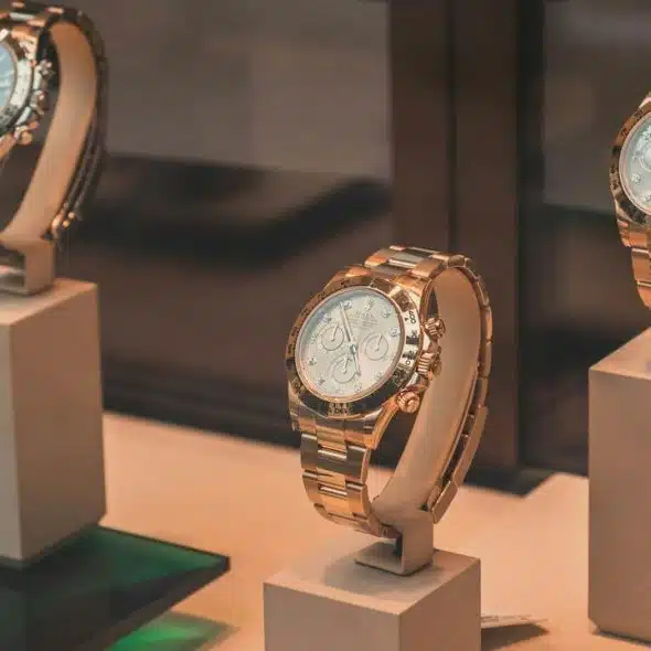 A trio of rose-gold chronograph watches on pedestal stands.