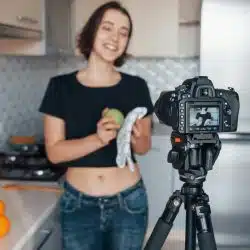 A woman filming a cooking video in a kitchen.
