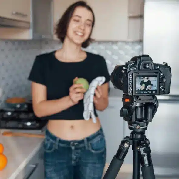 A woman filming a cooking video in a kitchen.