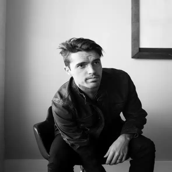 A man sitting down while wearing a leather jacket.