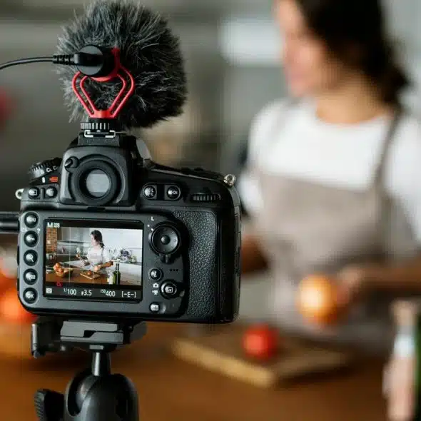A camera recording a woman cooking in a kitchen.