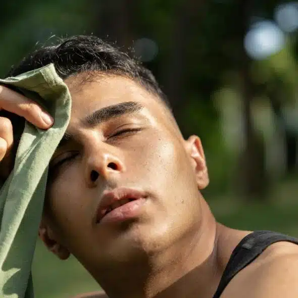 A man wiping sweat from his forehead on a hot day.