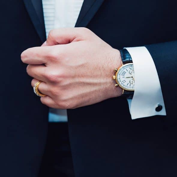 A man wearing a suit with his wristwatch shown.