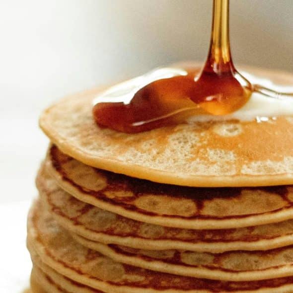 A stack of pancakes topped with butter and syrup.