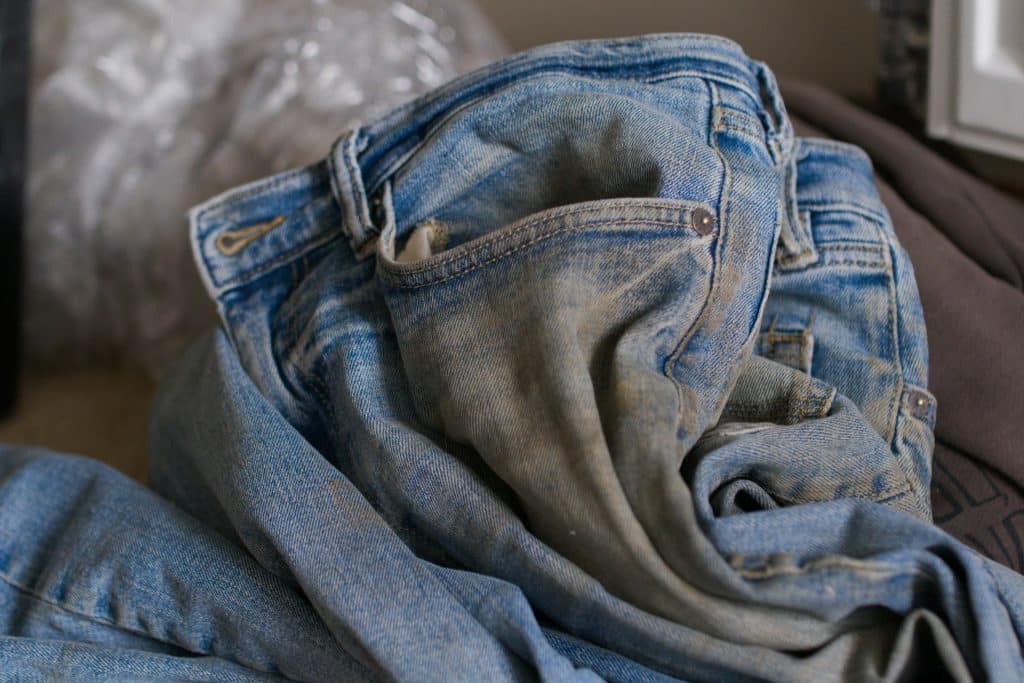 A pile of jeans sitting on top of a bed