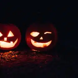 Two Pumpkin jack-o-lanterns glowing in the dark.