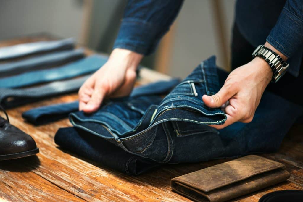 The person is folding the jeans.