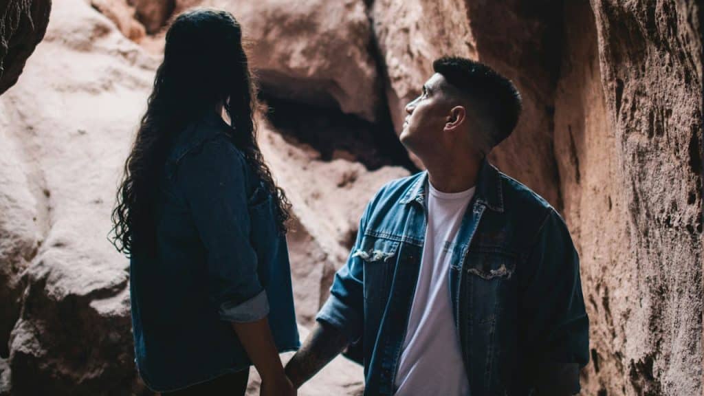 A man and a woman holding hands in a cave.