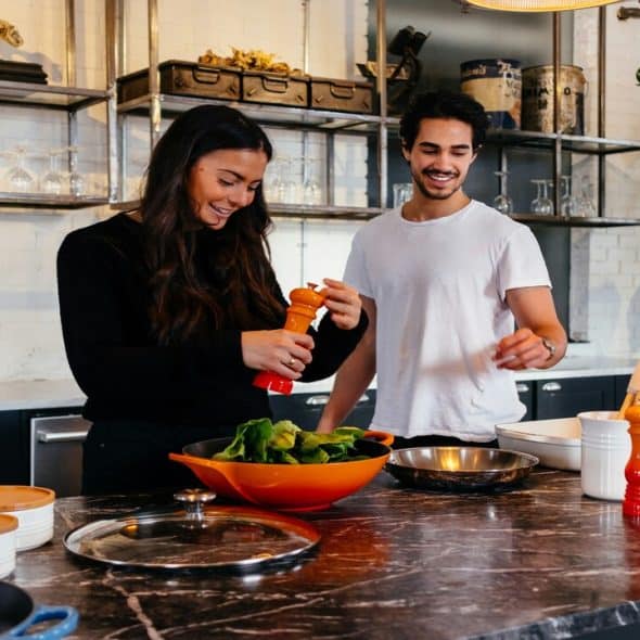 A couple cooking while smiling