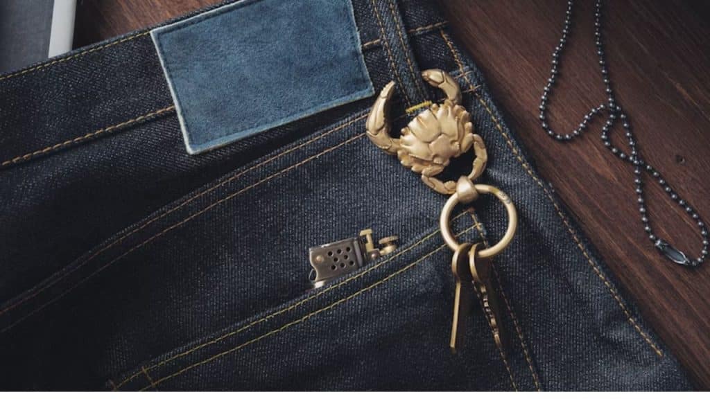Sturdy metal carabiner clipped on rugged man’s jeans