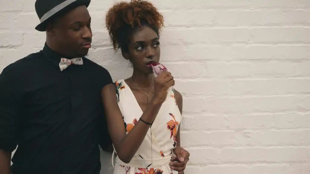 A man and a woman standing in front of a white-painted wall.