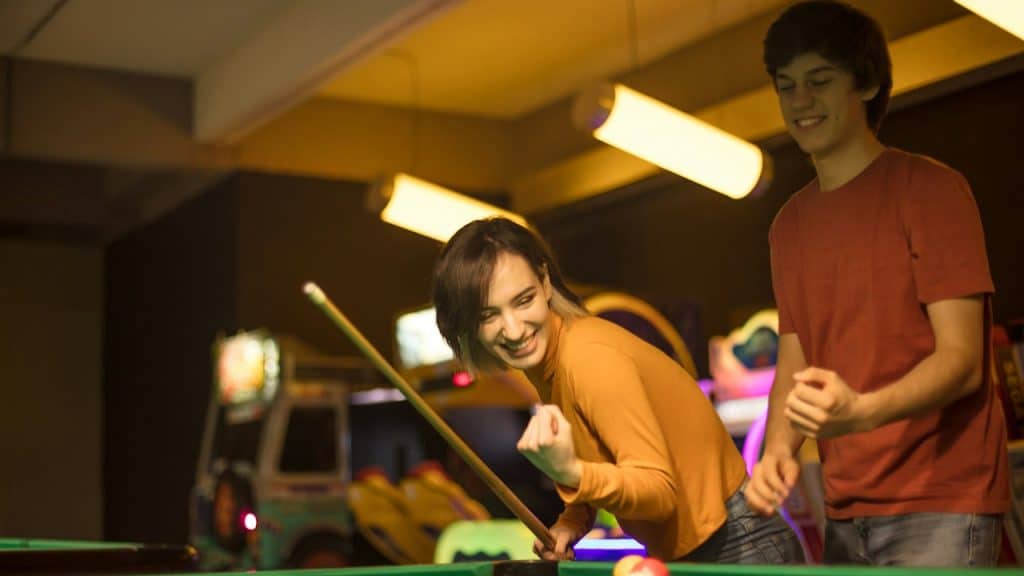A young couple spending time in a billiard room.