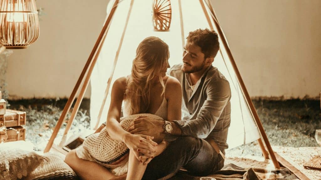 A couple sitting inside a tepee hut with lights.