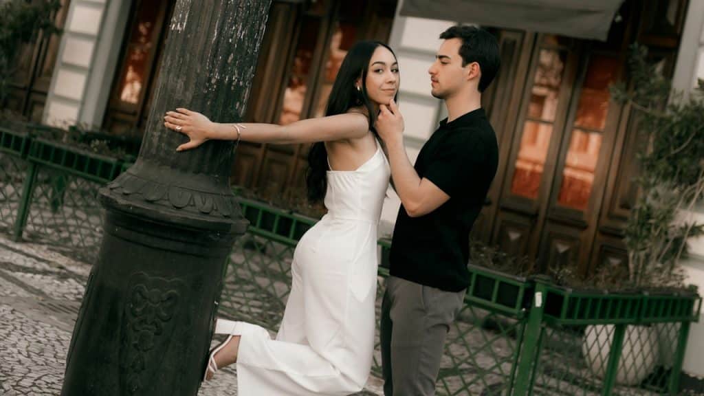 A couple posing by a lamppost on a cobblestone street.