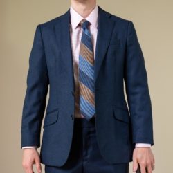 A person wearing a blue suit jacket over a pink shirt and striped tie.