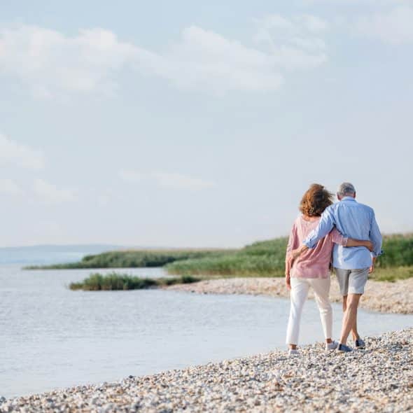 A photo of an old couple walking on the beach.