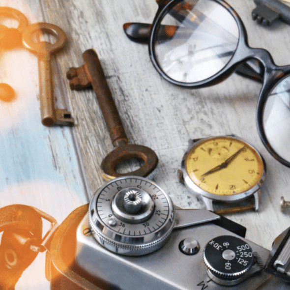 An old watch beside a film camera and glasses