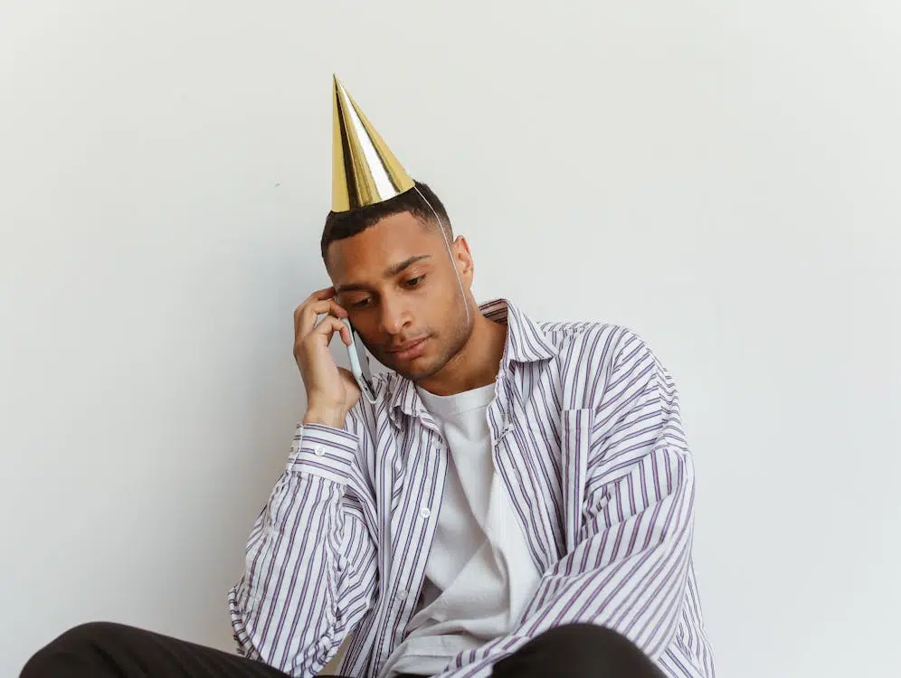 A Man in Party Hat while using Smartphone