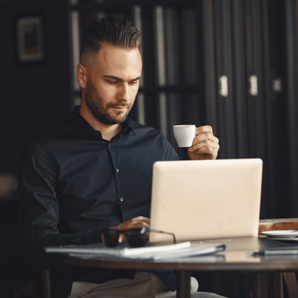 Man with Coffee Cup Working on Laptop